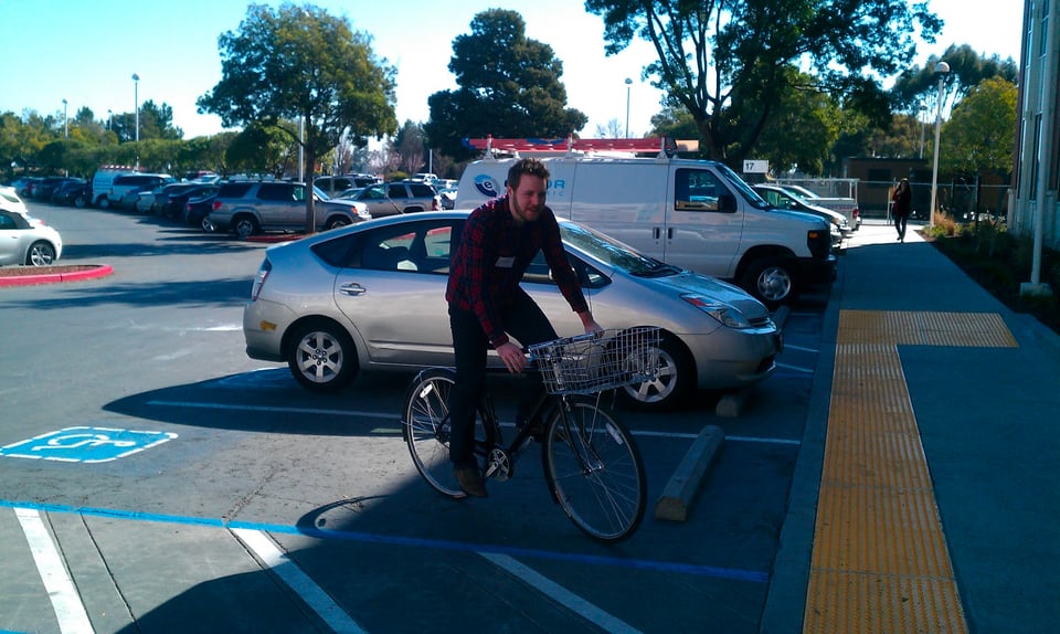 Your humble narrator, riding a Facebook bike around their parking lot in 2012